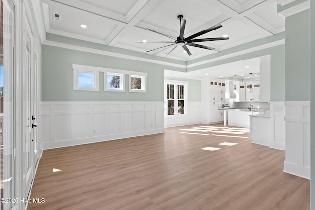 unfurnished living room with coffered ceiling, ceiling fan, ornamental molding, beam ceiling, and light hardwood / wood-style flooring