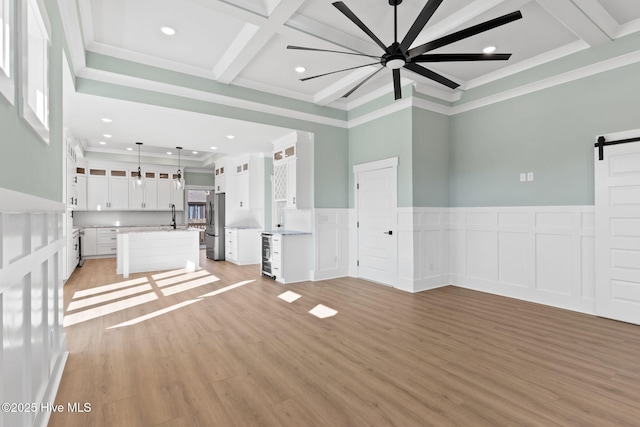 unfurnished living room featuring beverage cooler, coffered ceiling, a barn door, light hardwood / wood-style floors, and ceiling fan