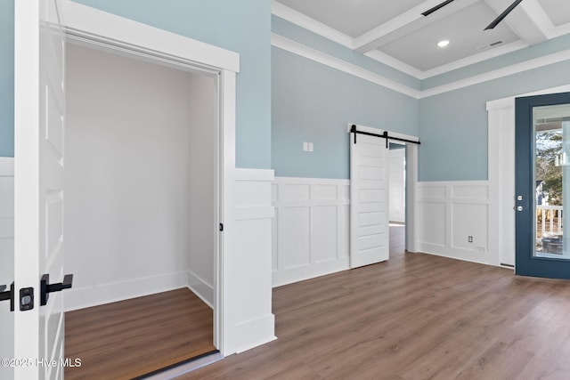 unfurnished bedroom with coffered ceiling, beamed ceiling, hardwood / wood-style floors, and a barn door