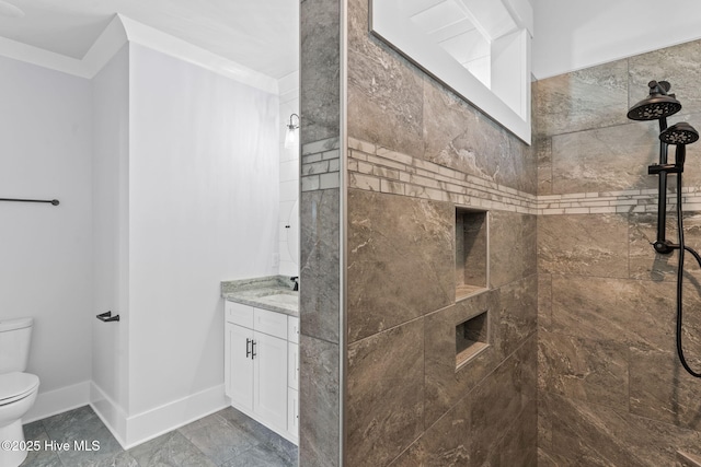 bathroom with toilet, tiled shower, and vanity