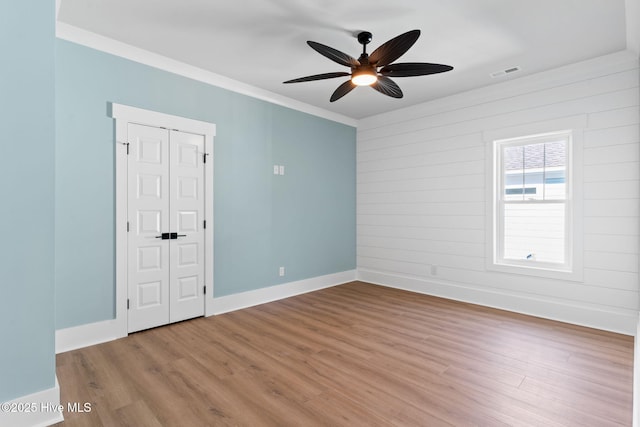 empty room with ceiling fan, light hardwood / wood-style floors, and crown molding