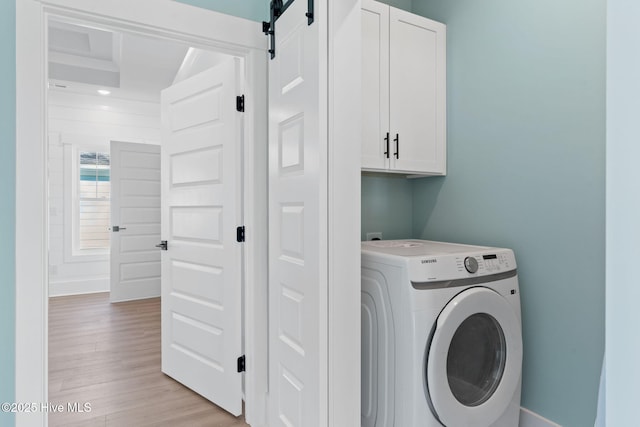 clothes washing area with cabinets, washer / clothes dryer, and light wood-type flooring