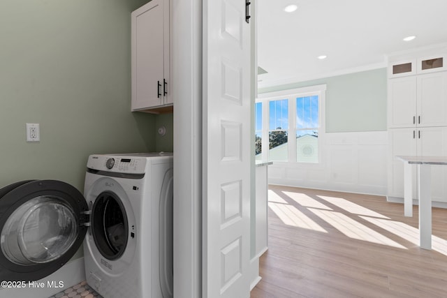 laundry room featuring crown molding, cabinets, washer and clothes dryer, and light wood-type flooring