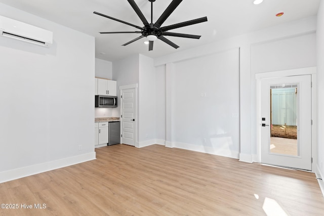 unfurnished living room featuring a wall unit AC, ceiling fan, and light hardwood / wood-style floors