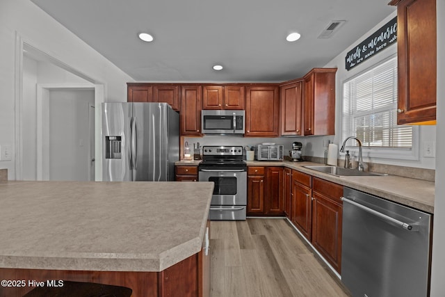 kitchen featuring appliances with stainless steel finishes, sink, and light wood-type flooring