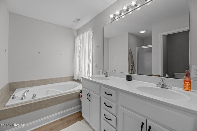 full bathroom with independent shower and bath, vanity, wood-type flooring, and toilet