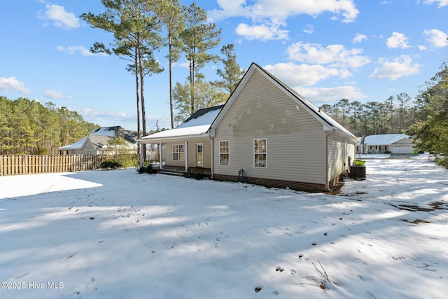 snow covered house featuring cooling unit and covered porch