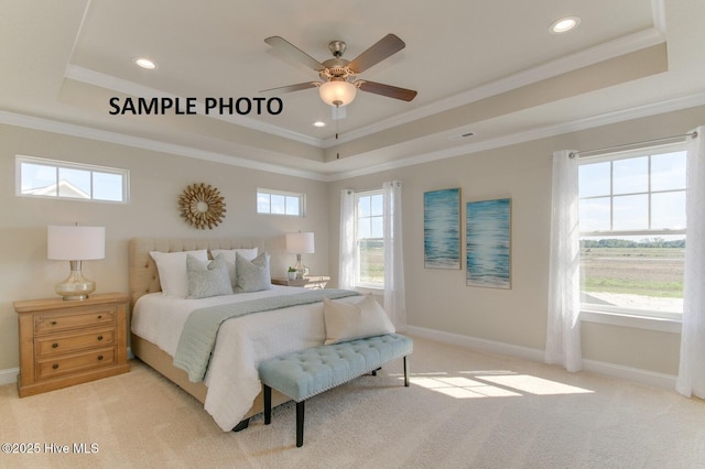 carpeted bedroom with a tray ceiling, multiple windows, ceiling fan, and ornamental molding