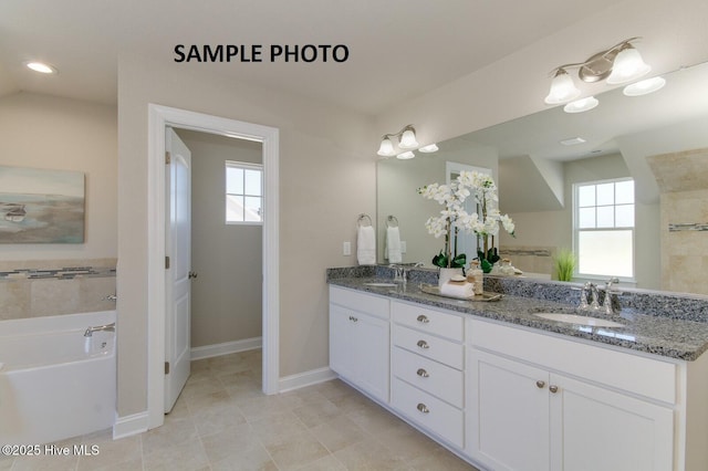 bathroom with a tub to relax in, vanity, and a healthy amount of sunlight