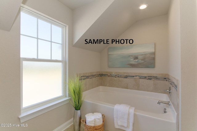 bathroom with a tub to relax in and lofted ceiling