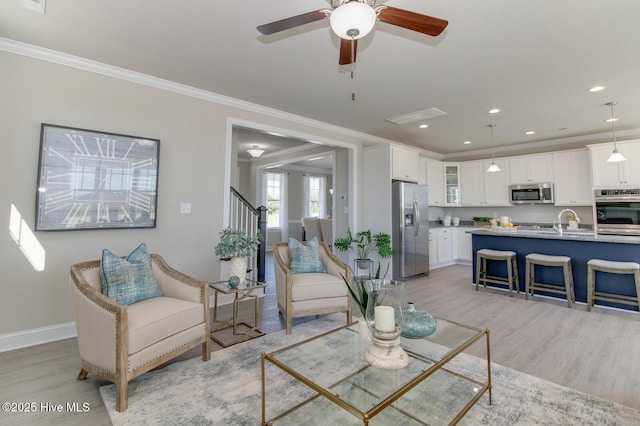 living room with ornamental molding, sink, and light hardwood / wood-style flooring