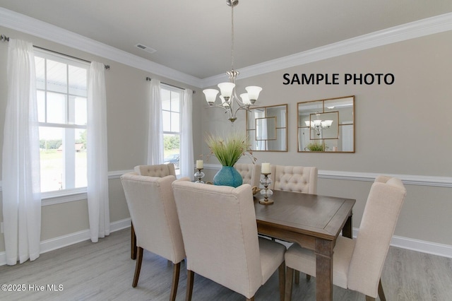 dining room with hardwood / wood-style flooring, plenty of natural light, crown molding, and a chandelier