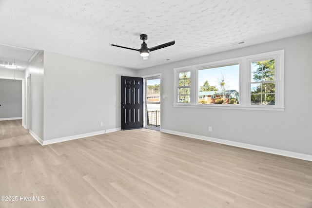 unfurnished room with ceiling fan, a textured ceiling, and light wood-type flooring