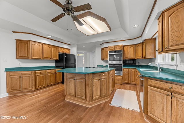 kitchen featuring sink, a center island, light wood-type flooring, and black appliances