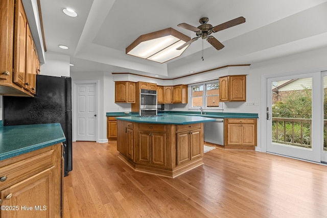 kitchen with a center island, a raised ceiling, ceiling fan, light hardwood / wood-style floors, and stainless steel dishwasher