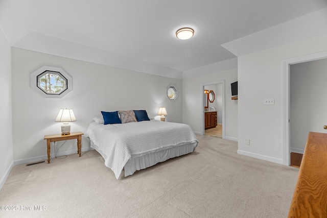 bedroom featuring ensuite bath and light carpet