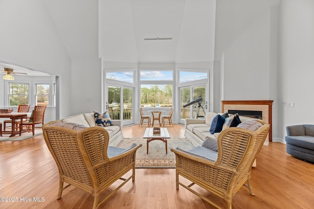 living room with a towering ceiling, light hardwood / wood-style flooring, and plenty of natural light