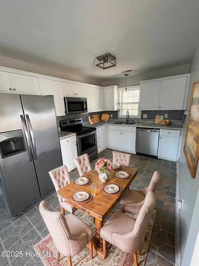 kitchen featuring sink, stainless steel appliances, backsplash, pendant lighting, and white cabinets