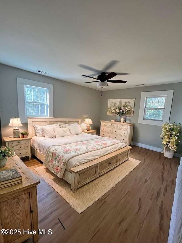 bedroom featuring multiple windows, ceiling fan, and hardwood / wood-style flooring