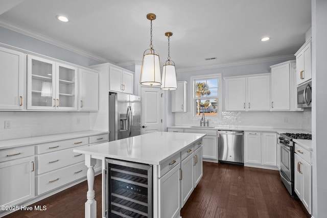 kitchen with white cabinets, sink, decorative light fixtures, stainless steel appliances, and beverage cooler