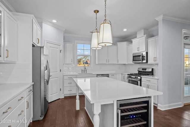 kitchen featuring hanging light fixtures, stainless steel appliances, white cabinets, and beverage cooler