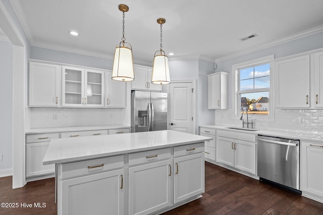 kitchen featuring stainless steel appliances, sink, decorative light fixtures, white cabinets, and a kitchen island