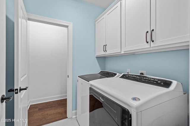 laundry area with washer and dryer, light hardwood / wood-style flooring, and cabinets