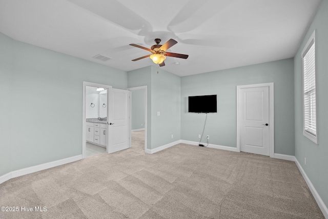 unfurnished bedroom featuring ensuite bath, ceiling fan, and light colored carpet