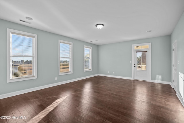 empty room with dark hardwood / wood-style floors and a wealth of natural light