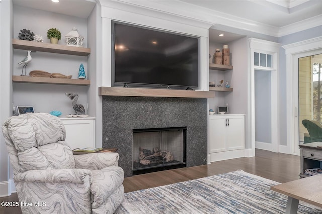 living room featuring crown molding, built in shelves, dark wood-type flooring, and a premium fireplace