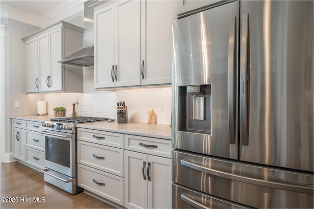 kitchen with dark wood-type flooring, stainless steel appliances, light stone counters, tasteful backsplash, and wall chimney exhaust hood