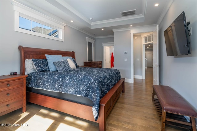 bedroom with ornamental molding, a raised ceiling, and wood-type flooring