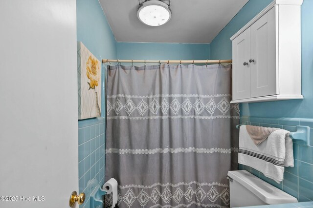 bathroom featuring toilet, tile walls, and walk in shower