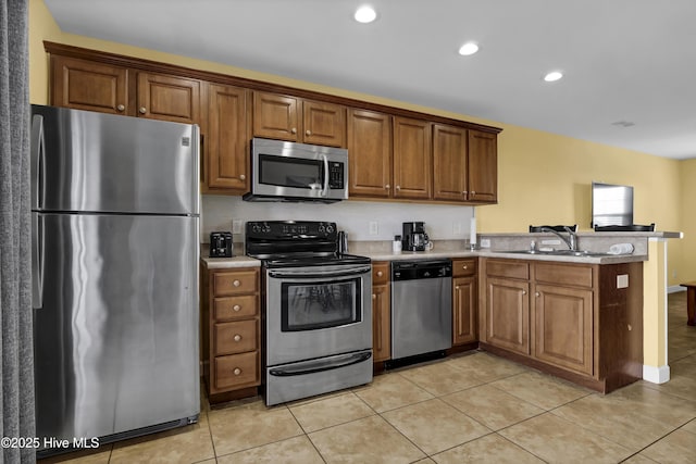 kitchen with kitchen peninsula, light tile patterned floors, sink, and appliances with stainless steel finishes