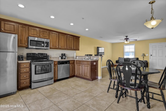 kitchen featuring kitchen peninsula, appliances with stainless steel finishes, ceiling fan, sink, and light tile patterned floors