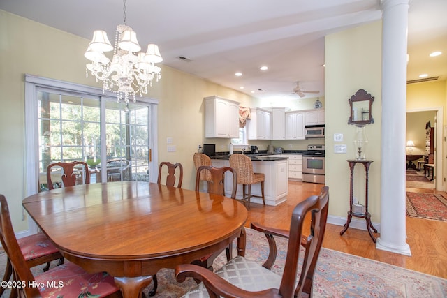 dining room with ceiling fan with notable chandelier, light hardwood / wood-style flooring, and ornate columns