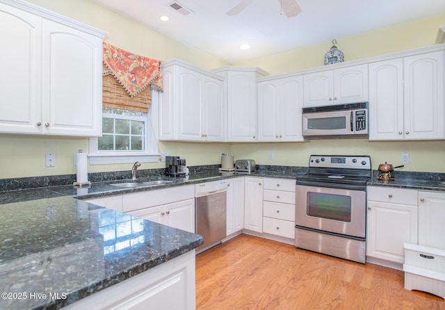 kitchen with appliances with stainless steel finishes, light hardwood / wood-style flooring, white cabinetry, and sink