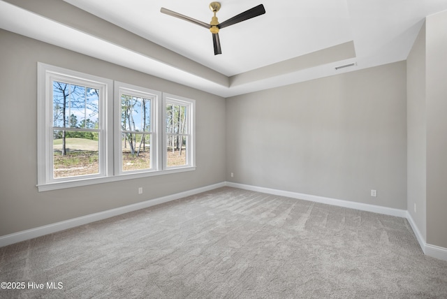 spare room featuring carpet, a tray ceiling, and ceiling fan