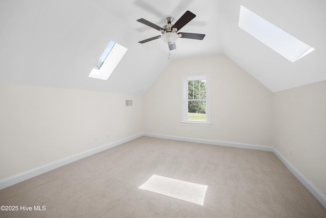 additional living space with vaulted ceiling with skylight, ceiling fan, and light carpet