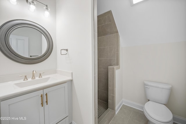 bathroom featuring tiled shower, tile patterned floors, vanity, and toilet