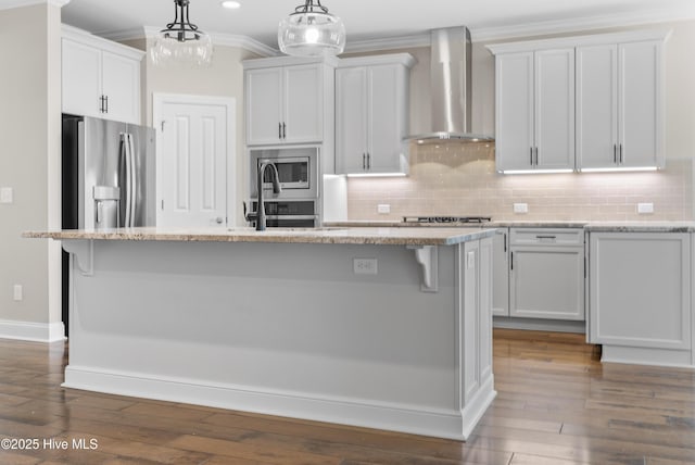 kitchen featuring white cabinets, wall chimney exhaust hood, and an island with sink