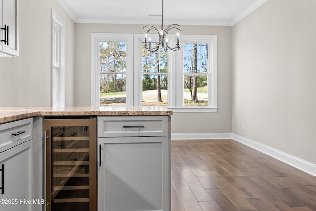 kitchen with crown molding, white cabinetry, hanging light fixtures, and beverage cooler