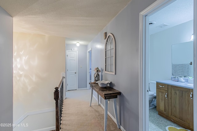 corridor featuring light carpet and a textured ceiling