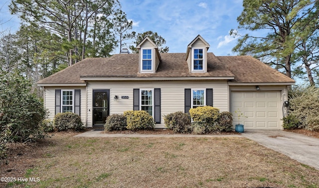 cape cod home featuring a garage and a front lawn