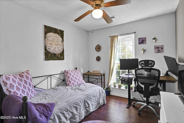 bedroom with ceiling fan, dark wood-type flooring, and a textured ceiling