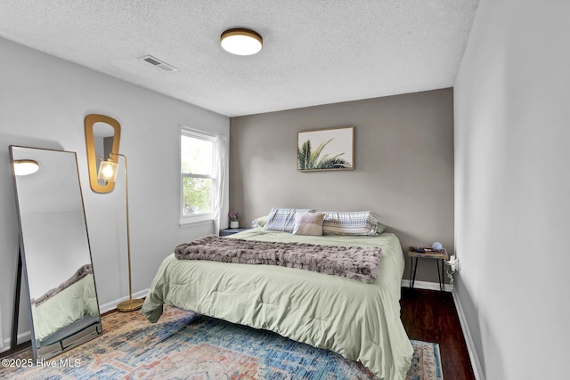 bedroom with a textured ceiling and dark hardwood / wood-style flooring