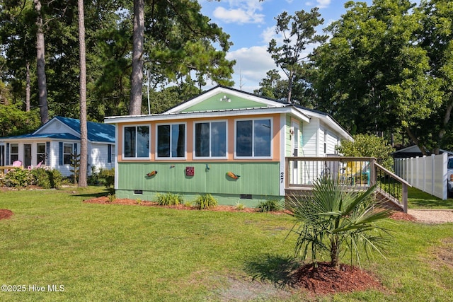 rear view of property with a sunroom, a deck, and a yard