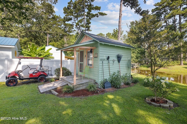 view of outbuilding featuring a water view and a lawn