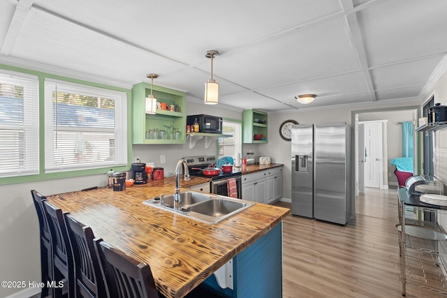 kitchen featuring kitchen peninsula, stainless steel appliances, sink, pendant lighting, and butcher block countertops