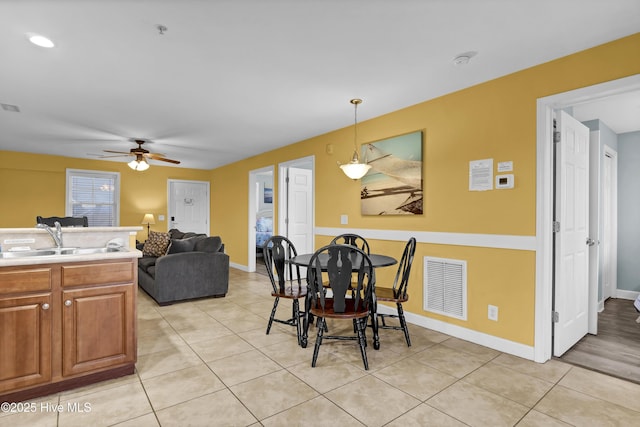 tiled dining space with ceiling fan and sink